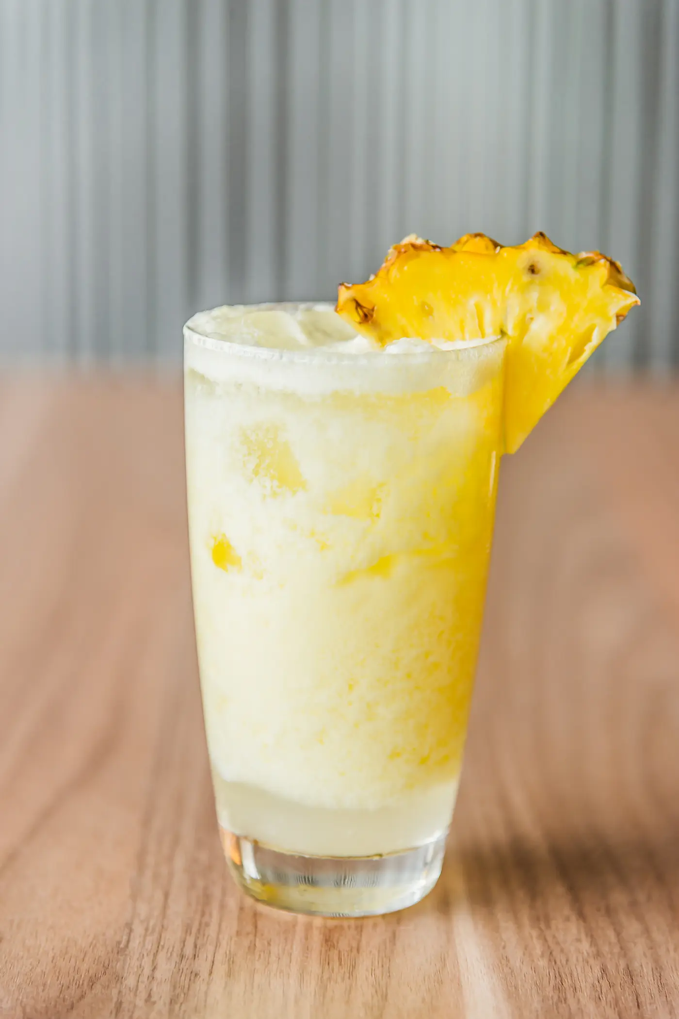 A glass of freshly pressed pineapple juice with a wedge of pineapple