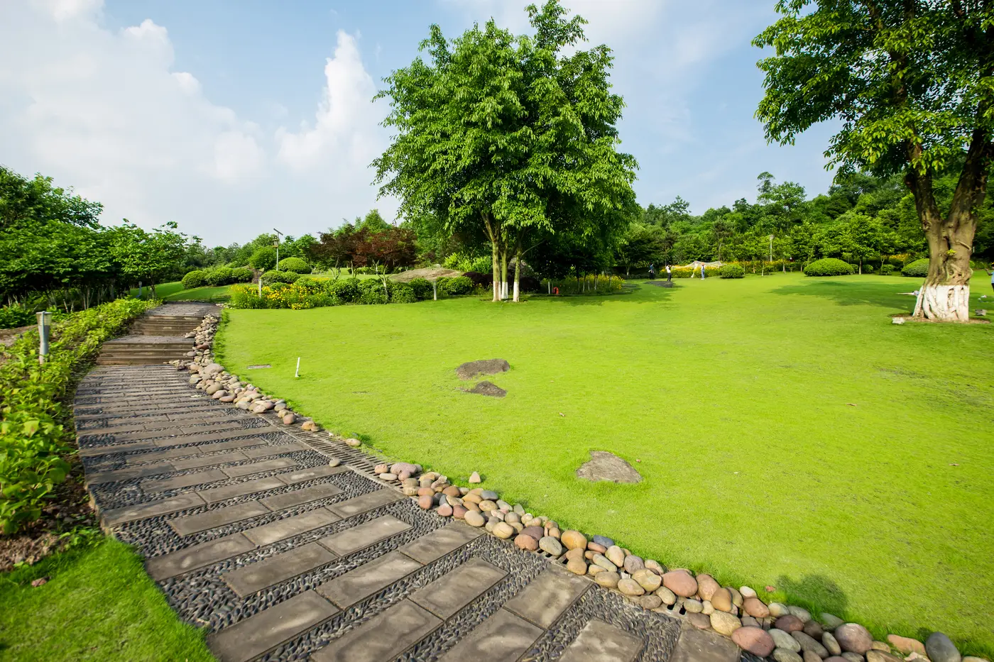 A stone path running beside the lawn under mature trees