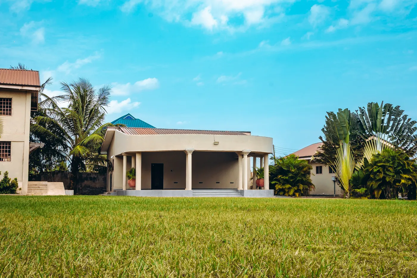 The terrace across the open lawn, palms to either side under a clear sky