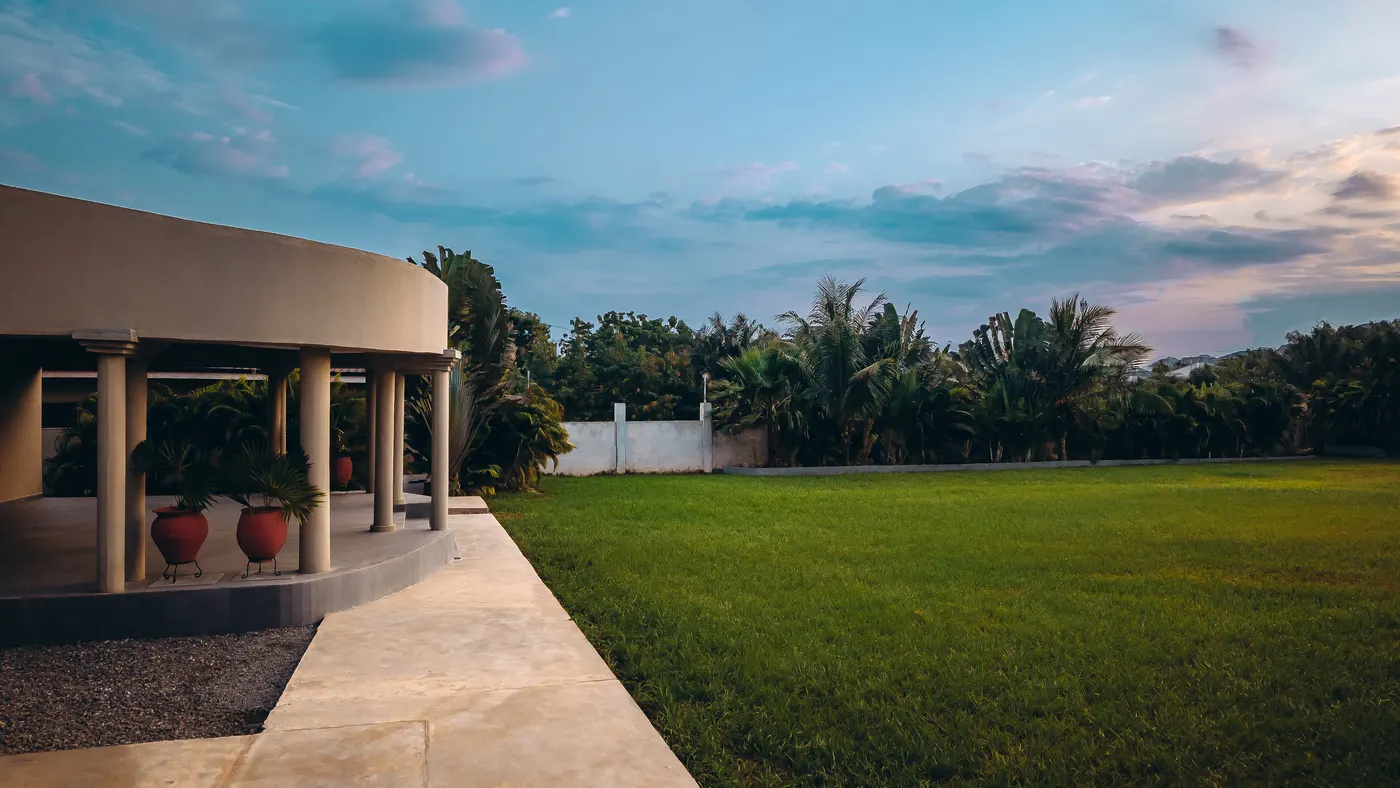 The terrace at dusk, the lawn beside it under a pink sky